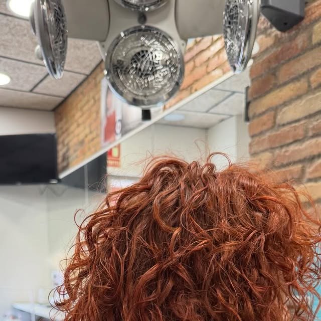 Rulls definits en color vermell coure, treball de la perruqueria Xtu